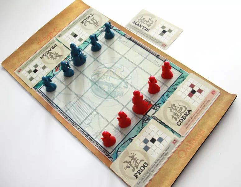 a playing mat with 10 pawns in their starting position (5 red one side, 5 blue on the other); two cards on each side, one next to the mat